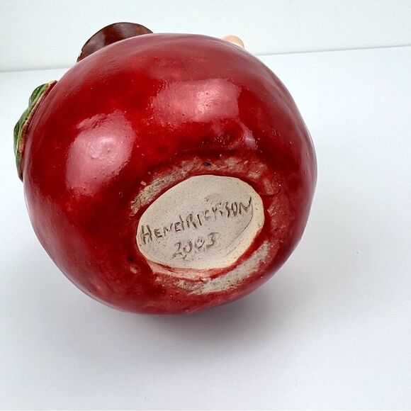 CARRIANNE L HENDRICKSON woman with beak hat sitting on apple sculpture 2… - Picture 9 of 16